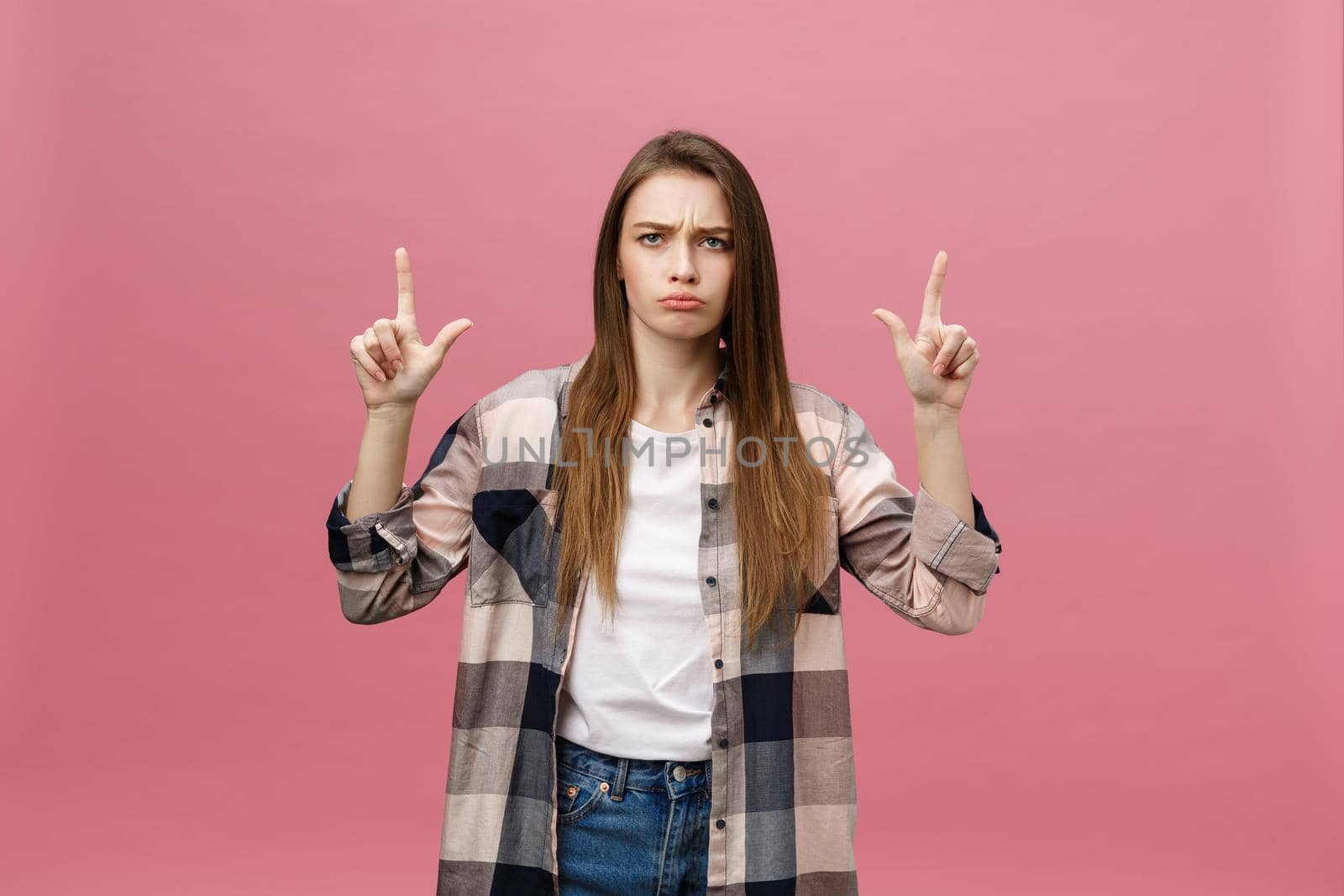 Portrait female pointing with finger with copy space for text or product, looking at the camera with serious expression. Advertising concept.