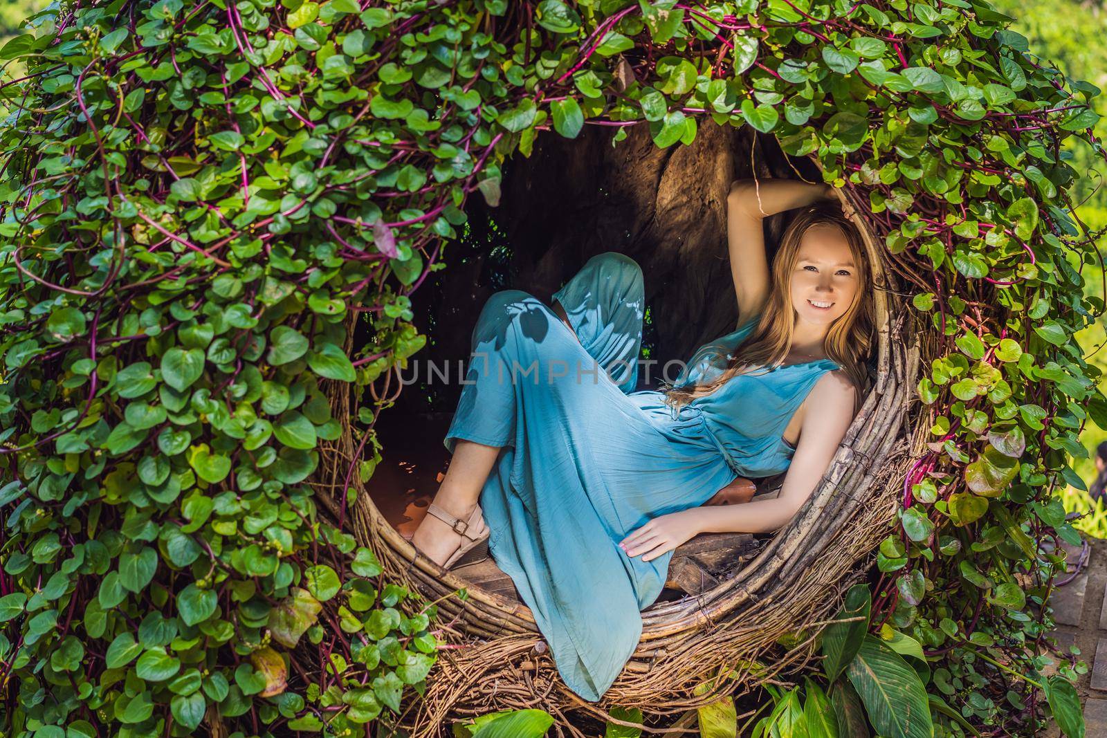Bali trend, straw nests everywhere. Young tourist enjoying her travel around Bali island, Indonesia. Making a stop on a beautiful hill. Photo in a straw nest, natural environment. Lifestyle.