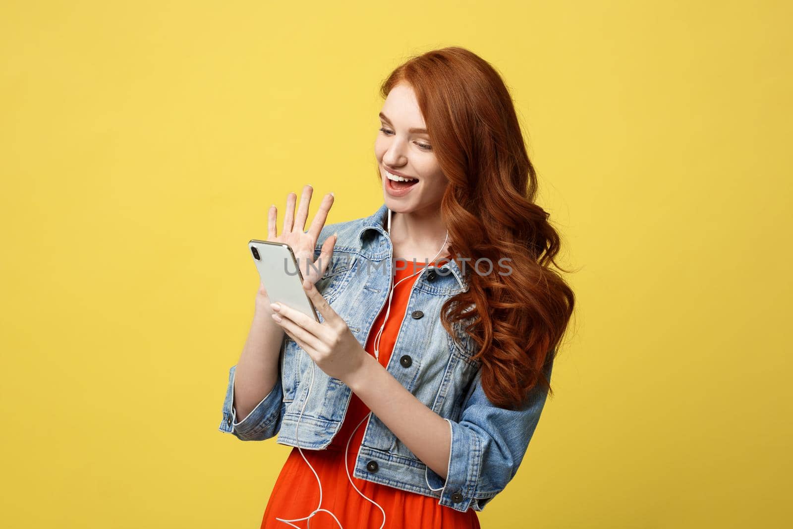 Lifestyle Concept: Young cheerful woman posing while photographing herself on smart phone camera for a chat with her friends, attractive smiling hipster girl making self portrait on cell telephone. by Benzoix