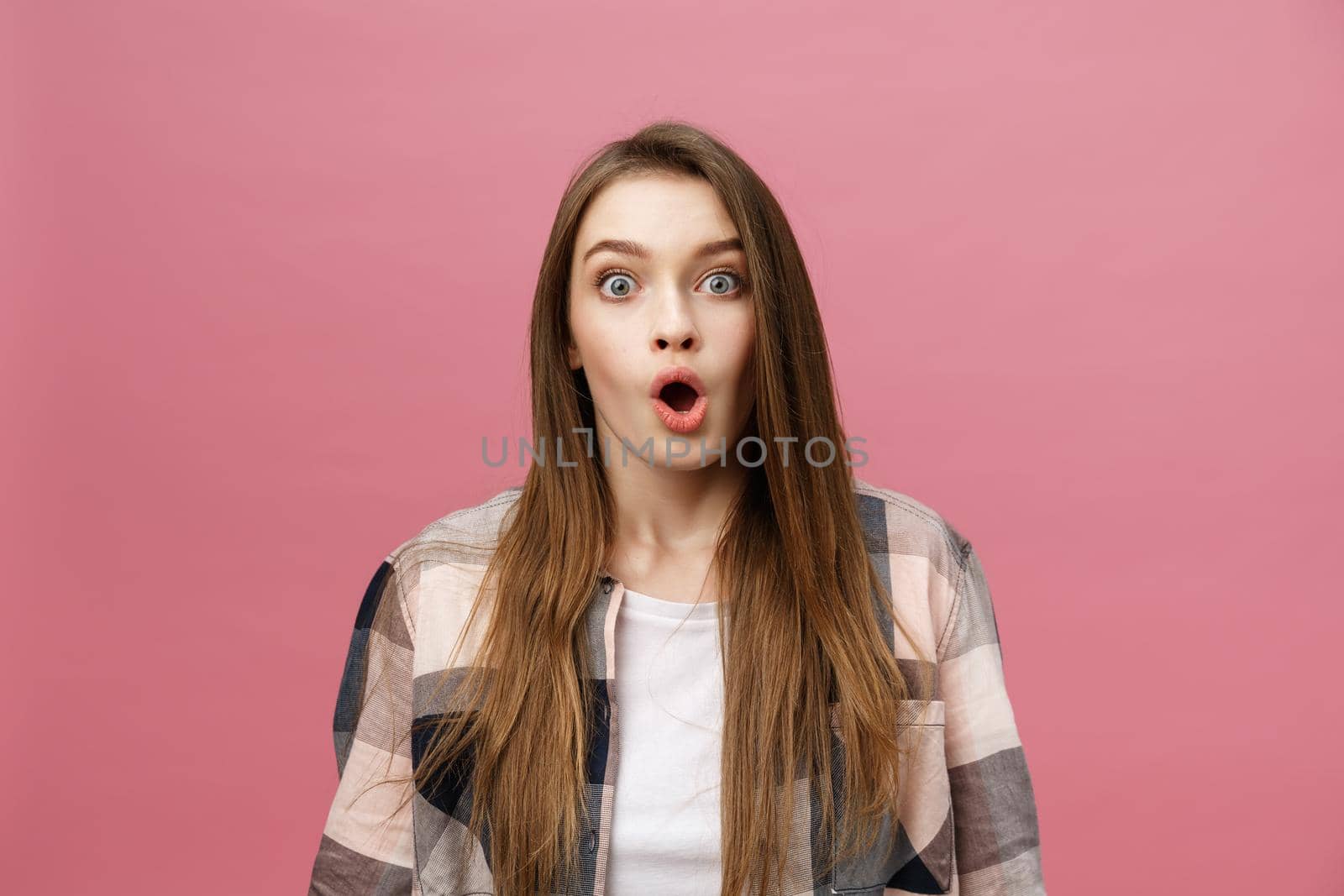 Surprised happy beautiful woman looking in excitement. Isolate over pink background and copy space. by Benzoix