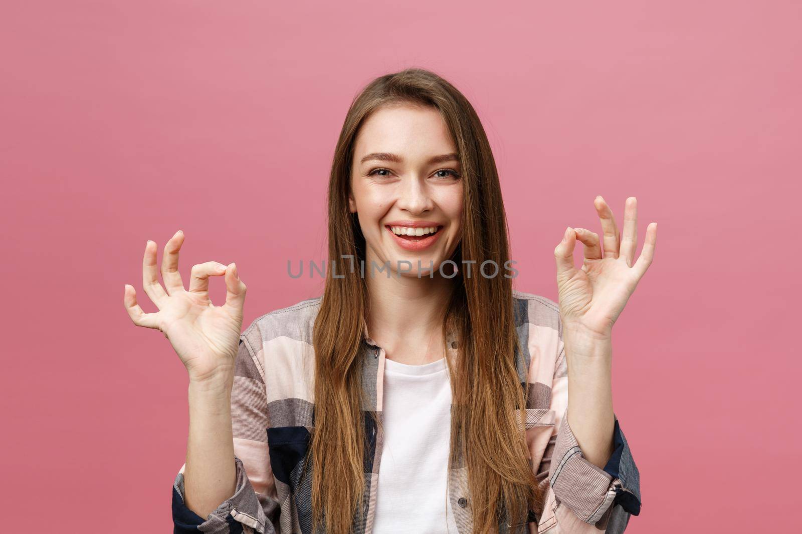 Attractive young adult woman showing ok sign. Expression emotion and feelings concept. Studio shot, isolated on pink background. by Benzoix