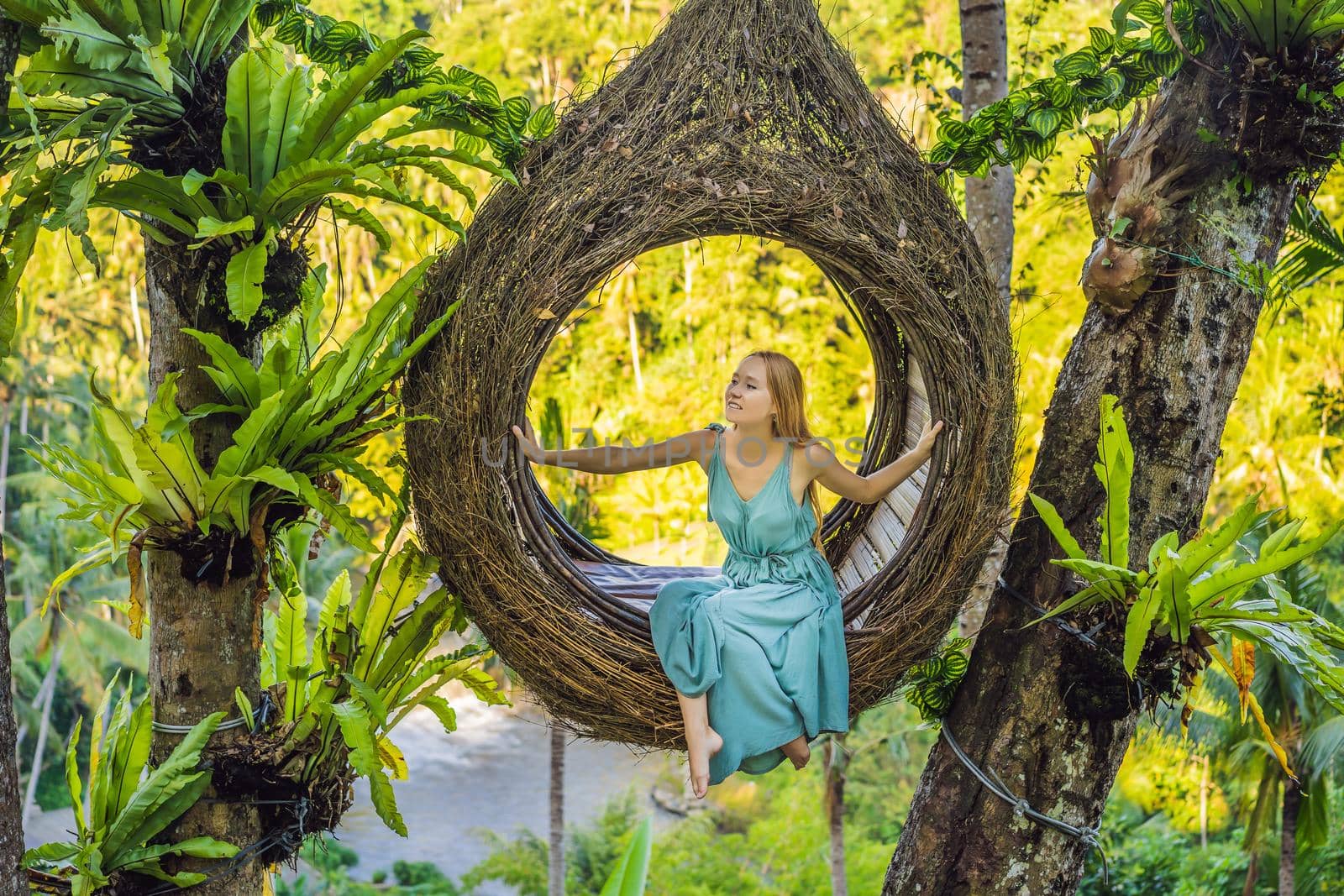 Bali trend, straw nests everywhere. Young tourist enjoying her travel around Bali island, Indonesia. Making a stop on a beautiful hill. Photo in a straw nest, natural environment. Lifestyle.