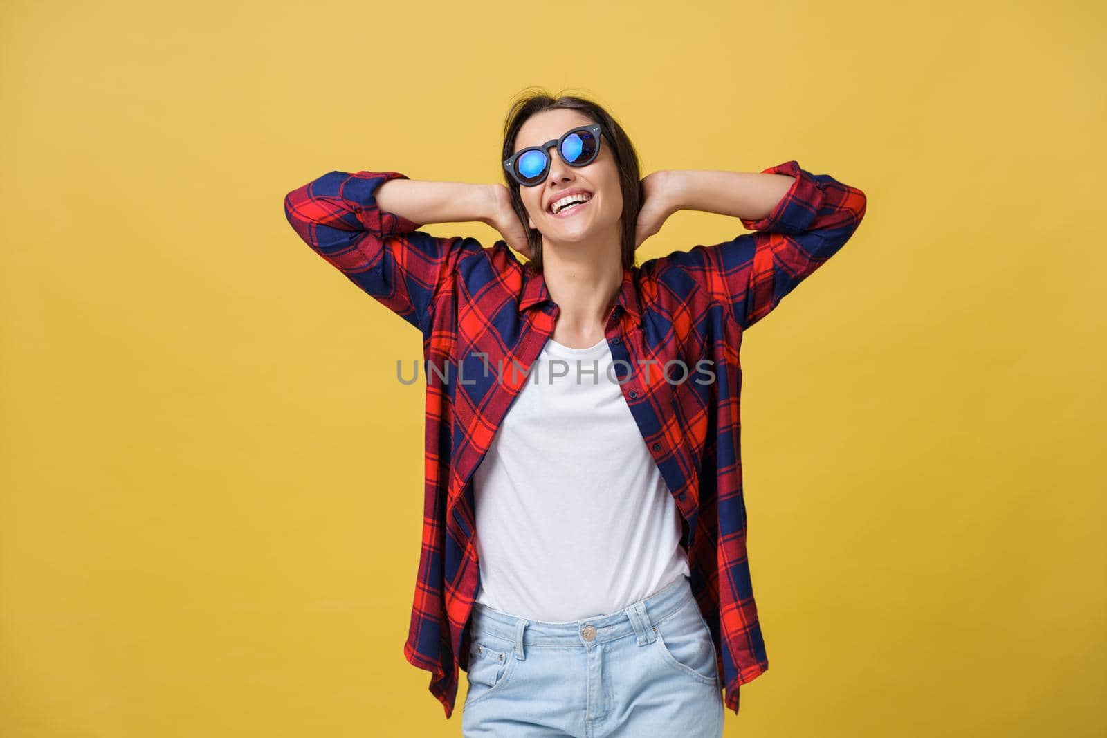 Happy stylish modern woman with modern shaped sunglasses laughing looking at you camera isolated on yellow background. Happiness concept by Benzoix