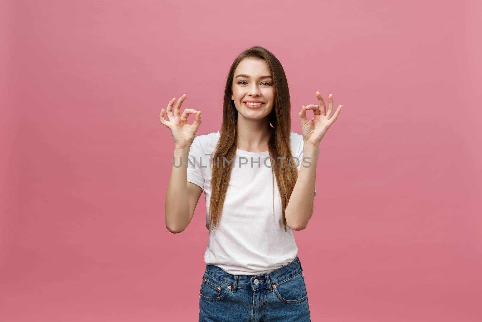 Attractive young adult woman showing ok sign. Expression emotion and feelings concept. Studio shot, isolated on pink background. by Benzoix