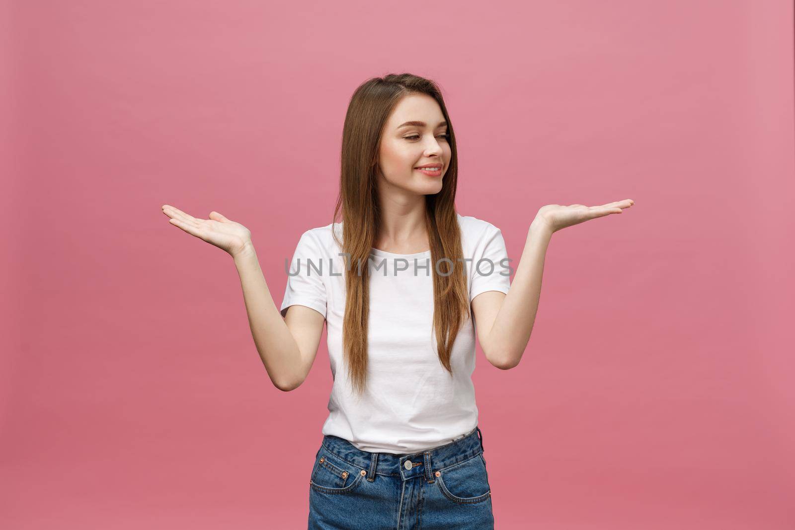 young girl with white shirt pointing hand on side to present a product on isolated pink background by Benzoix