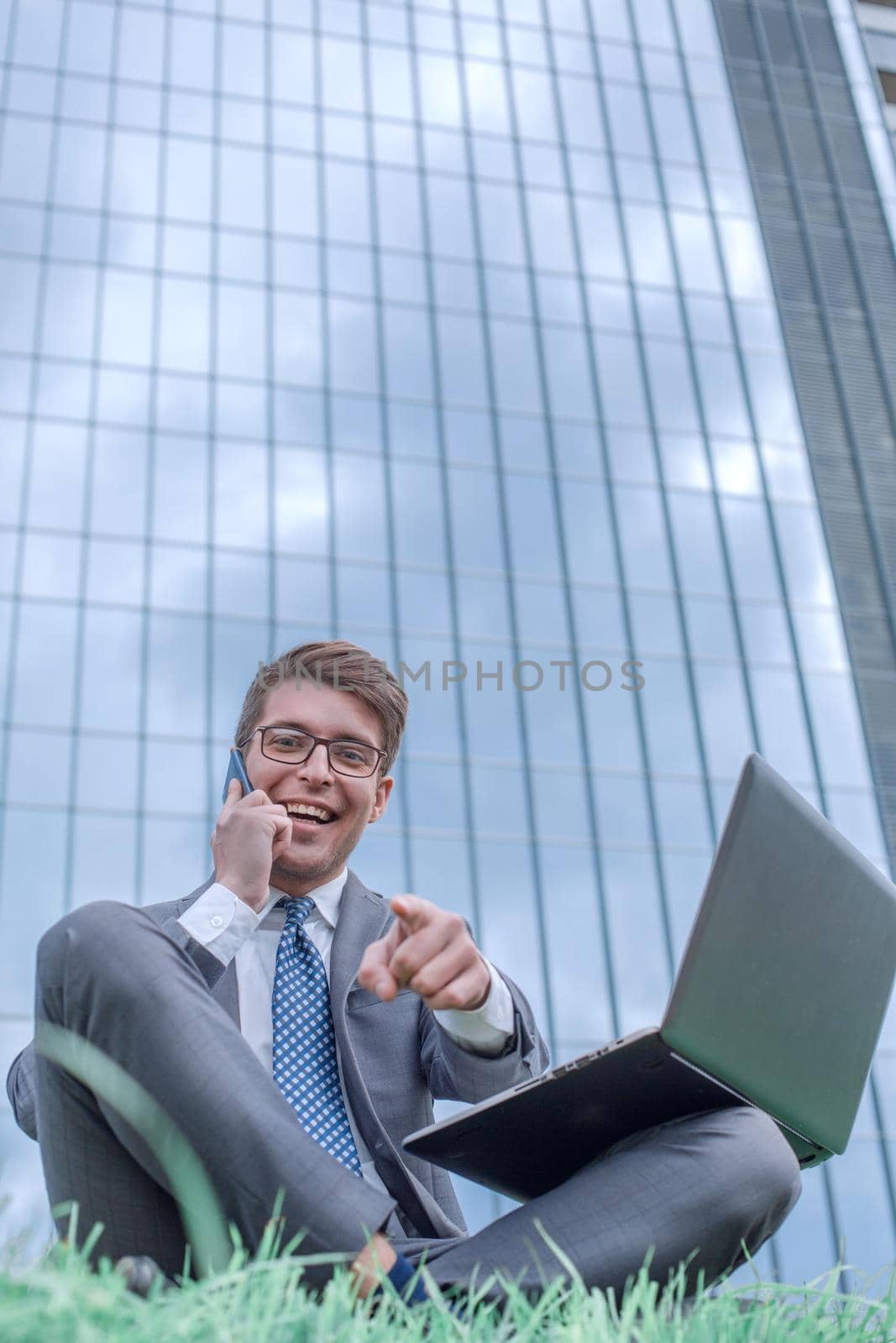 cheerful businessman speaks on his smartphone and points at you. photo with copy space