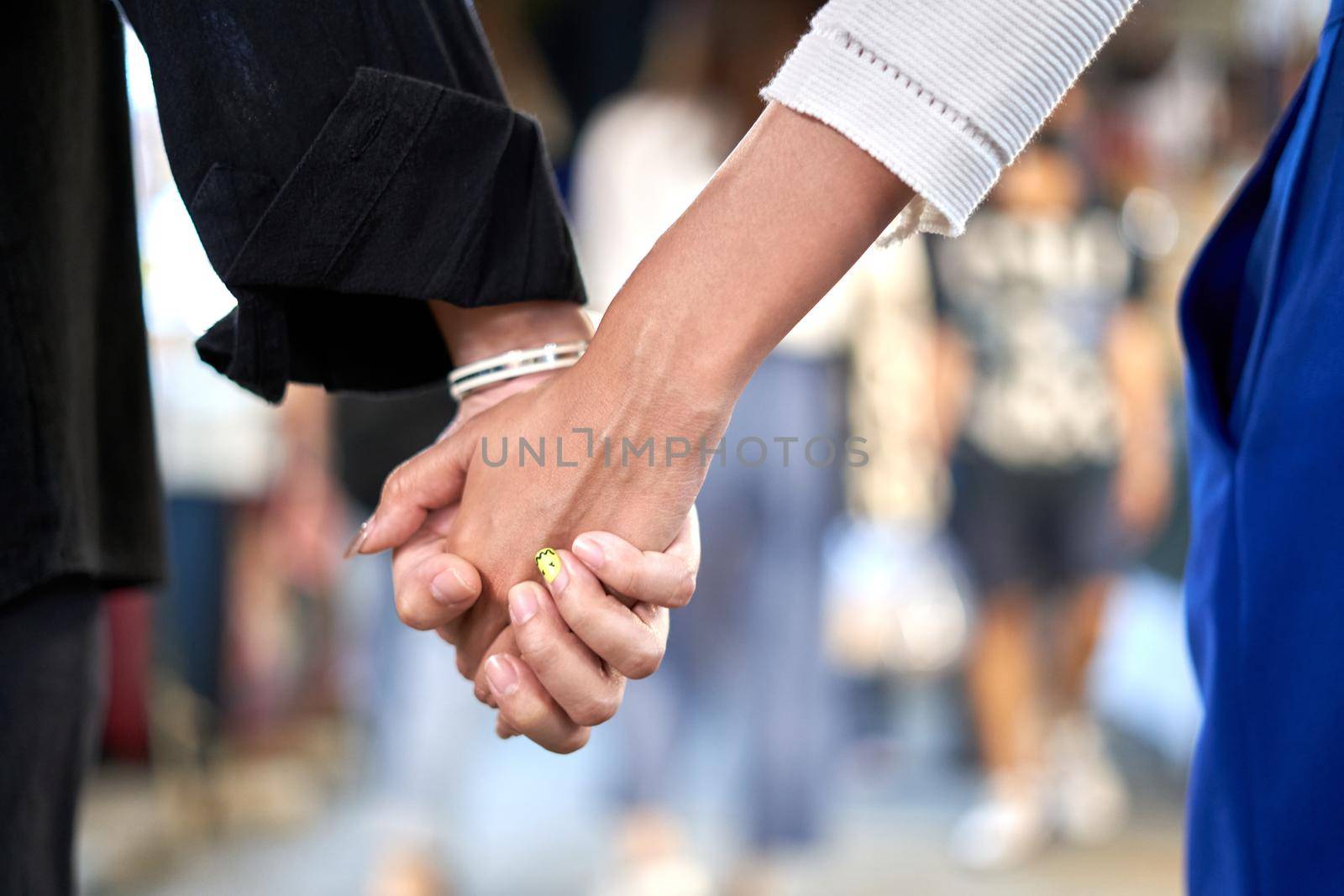 Lesbian couple's hands grabbed in the middle of an urban night market