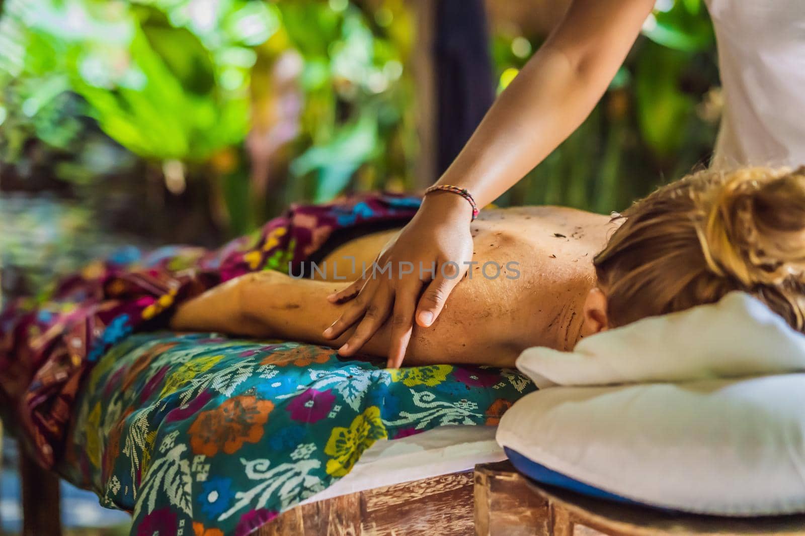 Young beautiful relaxing woman getting spa massage of shoulder in beauty salon.