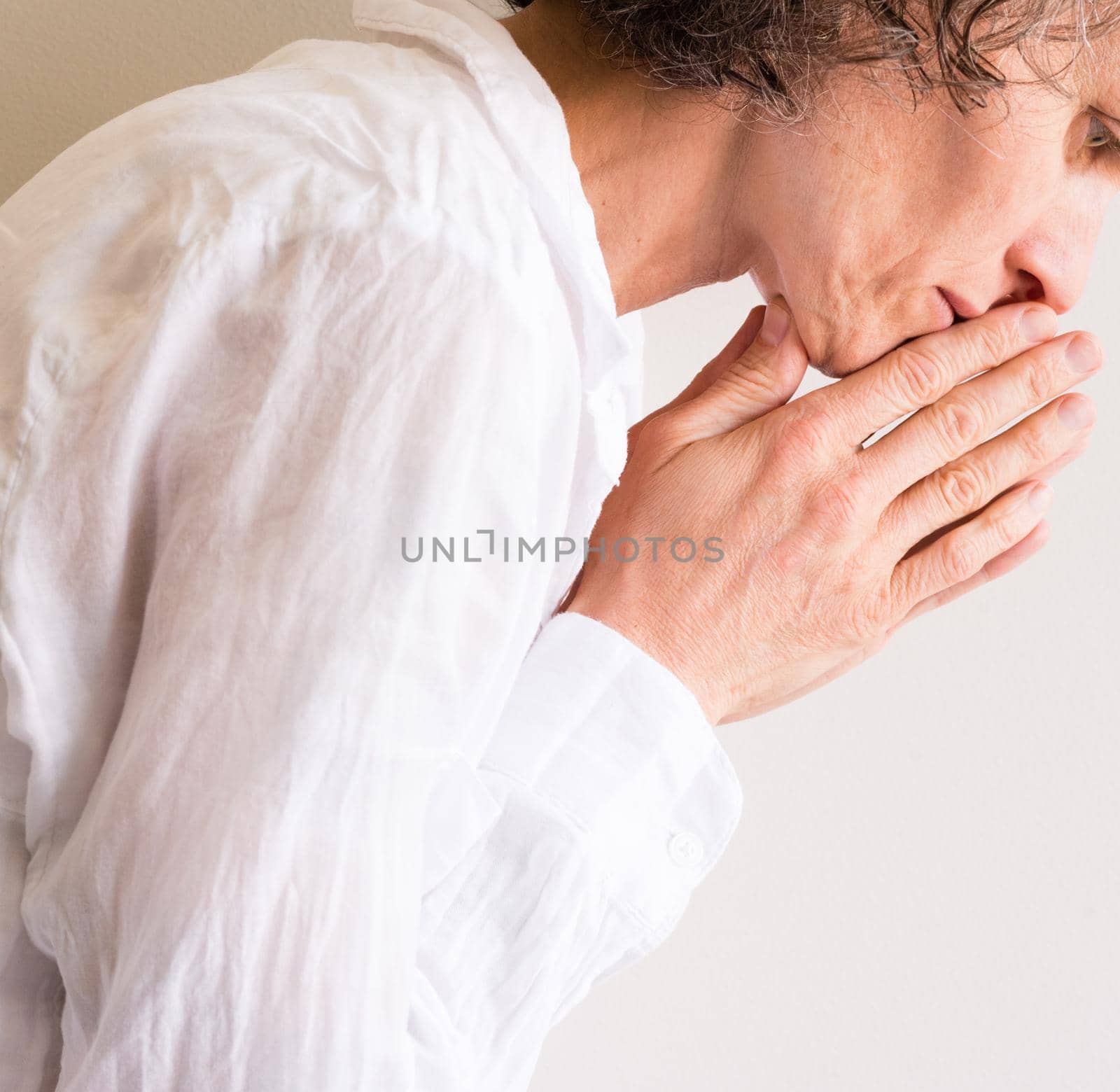Profile view of middle aged woman in white shirt praying against neutral background (cropped)