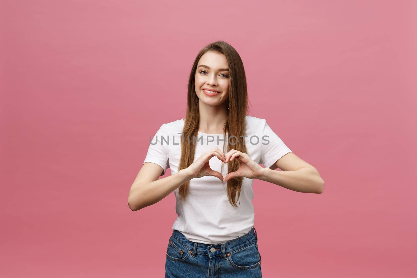 Lifestyle Concept: Beautiful attractive woman in white shirt making a heart symbol with her hands.