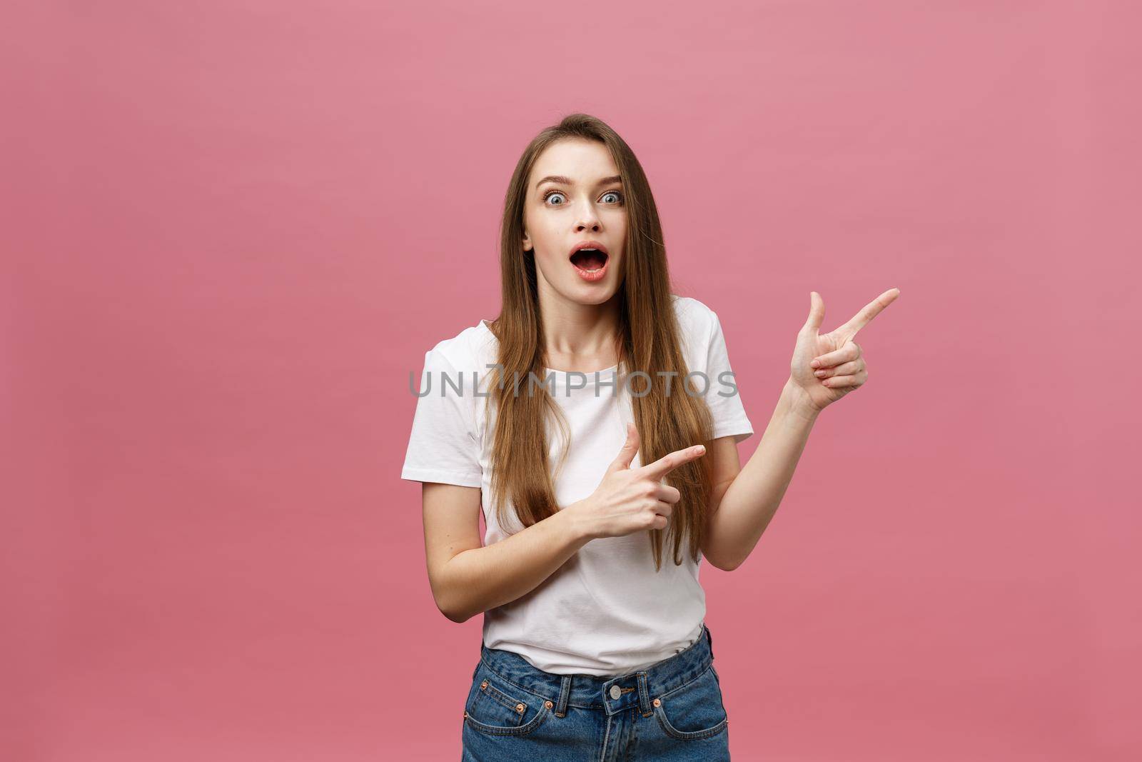 Woman pointing finger at camera and toothy smiling. Expression emotion and feelings concept. Studio shot, isolated on pink background by Benzoix