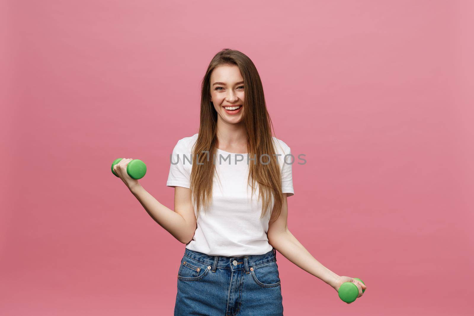 Fitness, young woman with dumbbells at studio background. Pretty girl isolate over pink by Benzoix