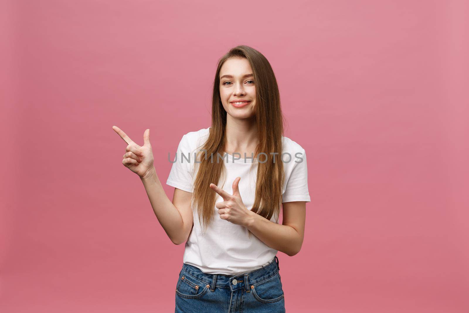 Photo of happy young woman standing and poiting finger isolated over pink background. by Benzoix