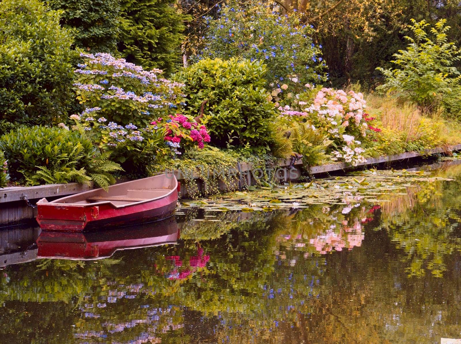 Romantic image of the river Eem in Holland, a rowing boat and a garden. Reflections in the water