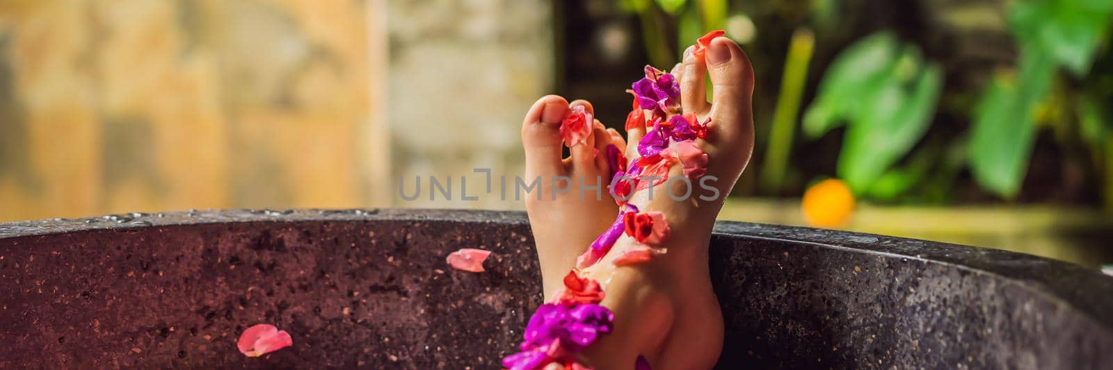 Attractive Young woman in bath with petals of tropical flowers and aroma oils. Spa treatments for skin rejuvenation. Alluring woman in Spa salon. Girl relaxing in bathtub with flower petals. Luxury. BANNER, LONG FORMAT