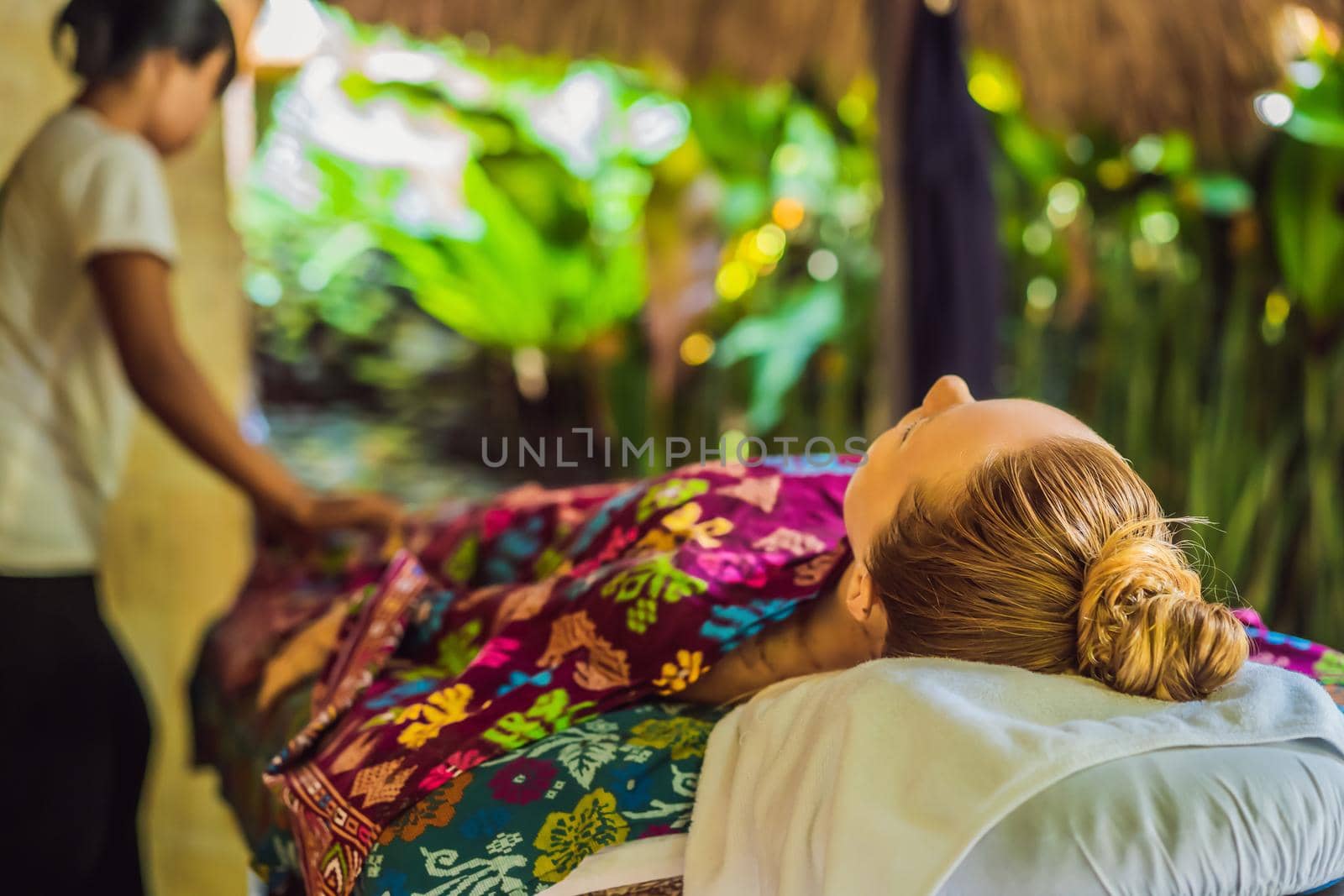 Young beautiful relaxing woman getting spa massage of shoulder in beauty salon.