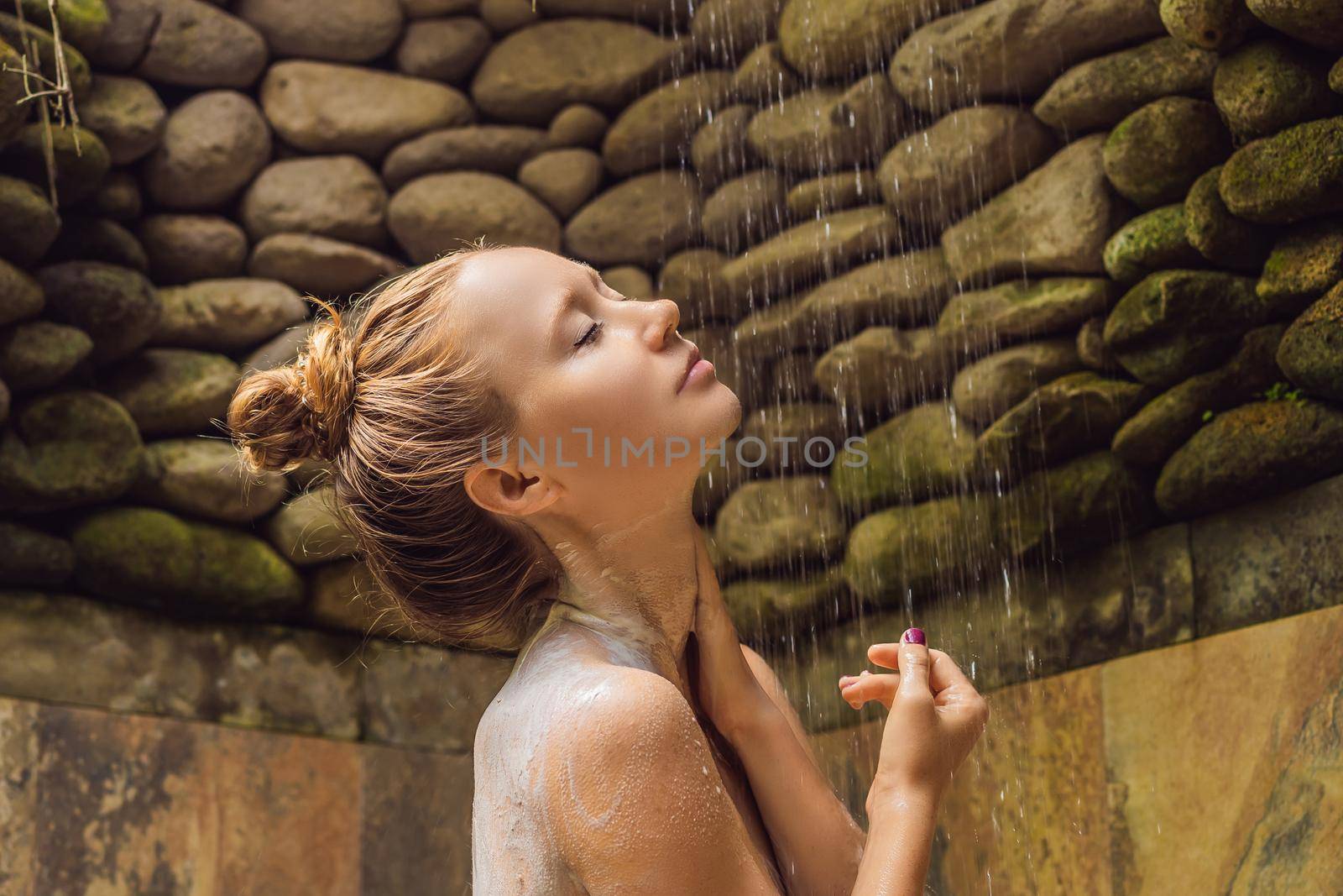 Back view of beautiful naked young woman taking shower in bathroom.