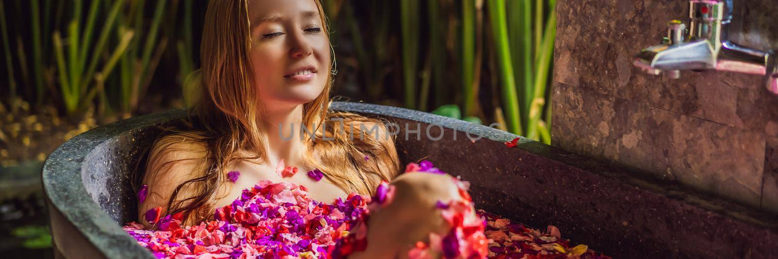 Attractive Young woman in bath with petals of tropical flowers and aroma oils. Spa treatments for skin rejuvenation. Alluring woman in Spa salon. Girl relaxing in bathtub with flower petals. Luxury BANNER, LONG FORMAT by galitskaya