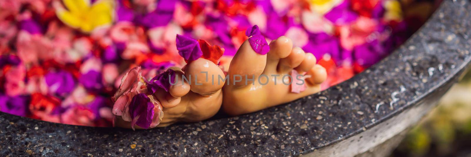 Attractive Young woman in bath with petals of tropical flowers and aroma oils. Spa treatments for skin rejuvenation. Alluring woman in Spa salon. Girl relaxing in bathtub with flower petals. Luxury. BANNER, LONG FORMAT