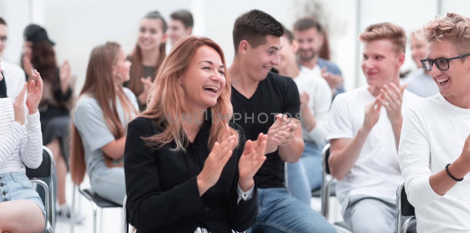 close up. smiling young woman applauding sitting in conference room by asdf