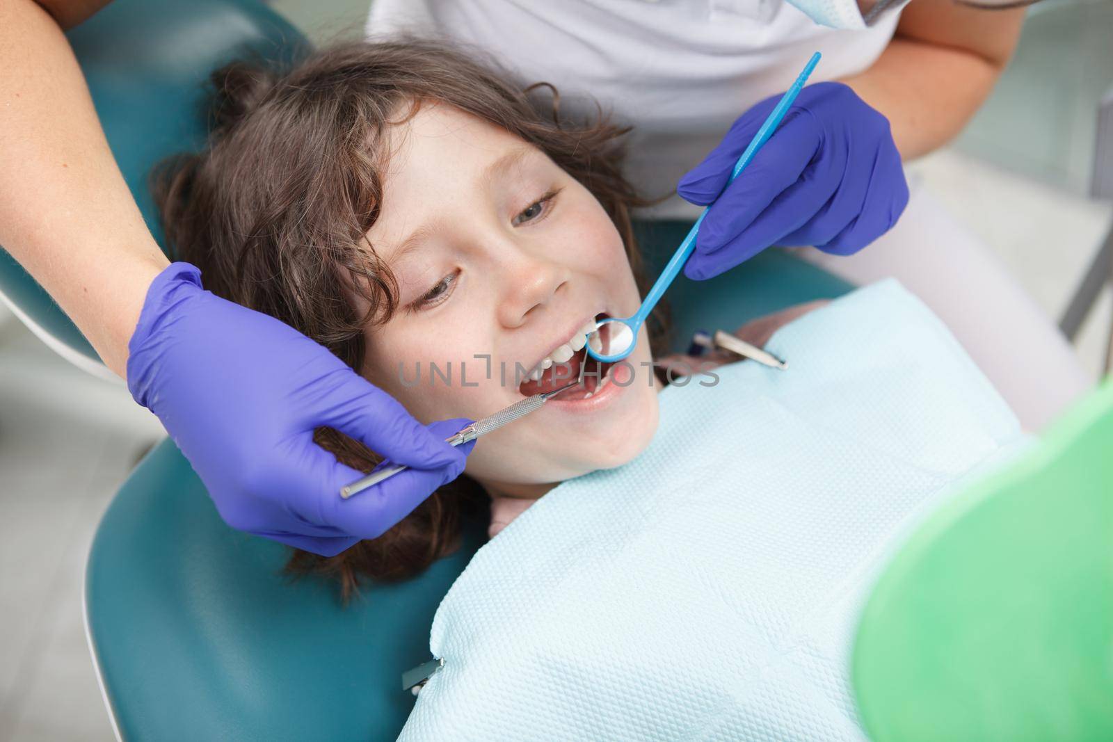 Close up of a lovely cheerful young boy getting his teeth checked by dentist