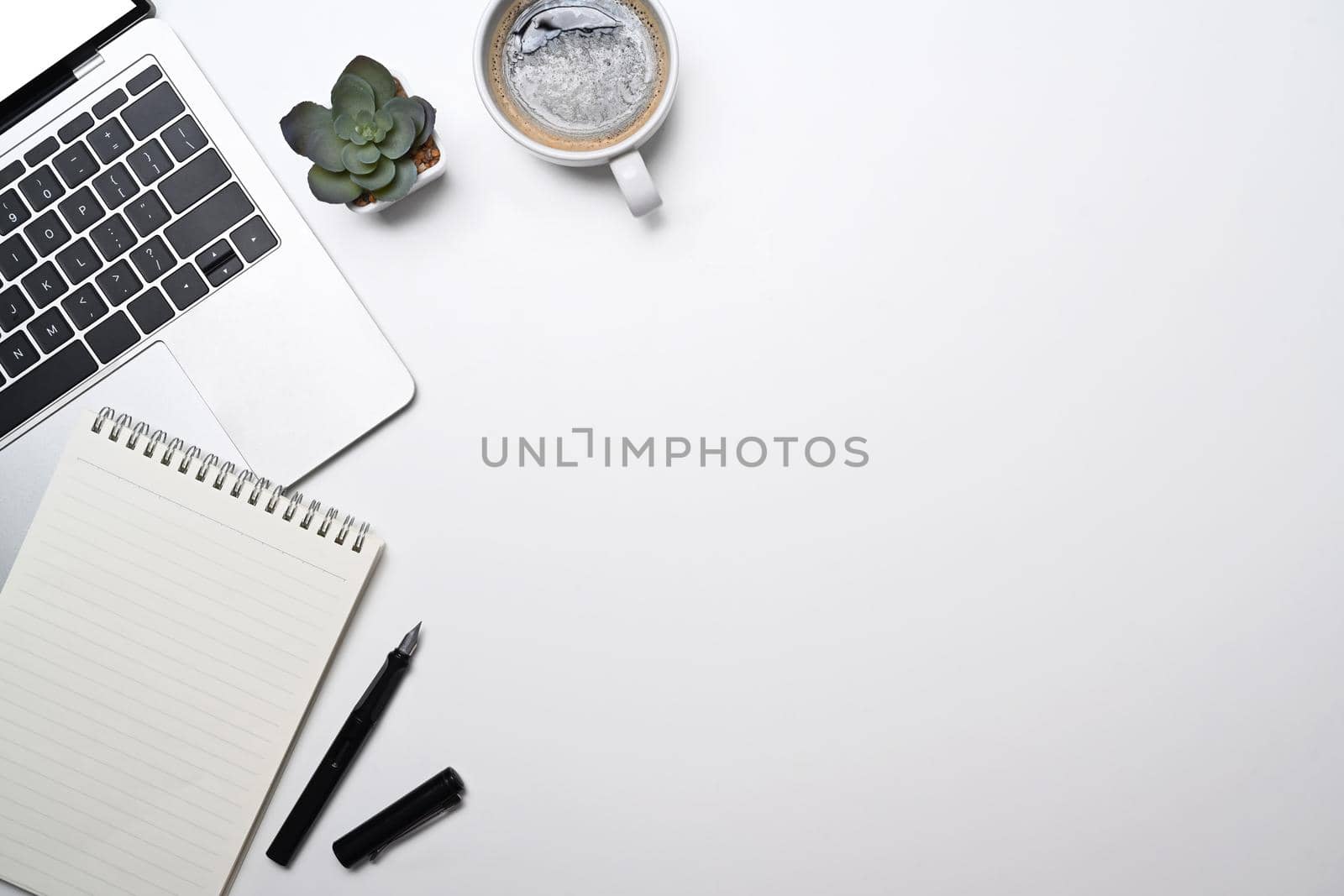 Minimal workplace with laptop computer, coffee cup, blank notepad and succulent plant. Top view with copy space.