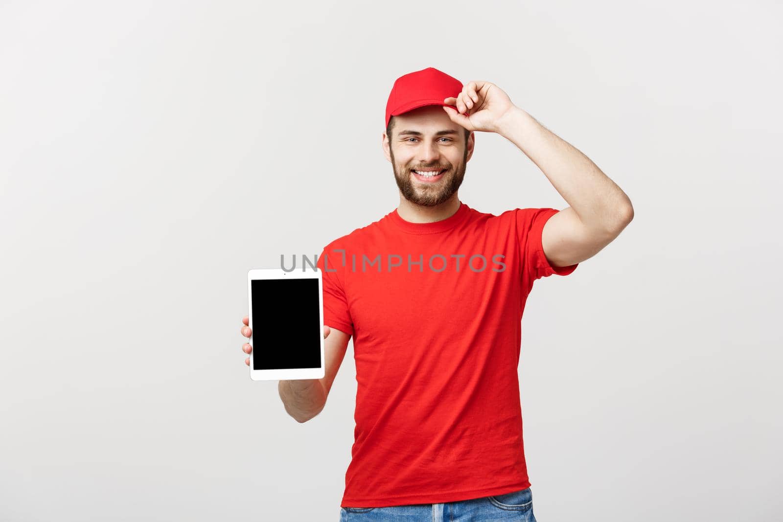 Online shopping, delivery, technology and lifestyle concept - smiling delivery man presenting tablet in his hand showing something. Isolated over white studio background