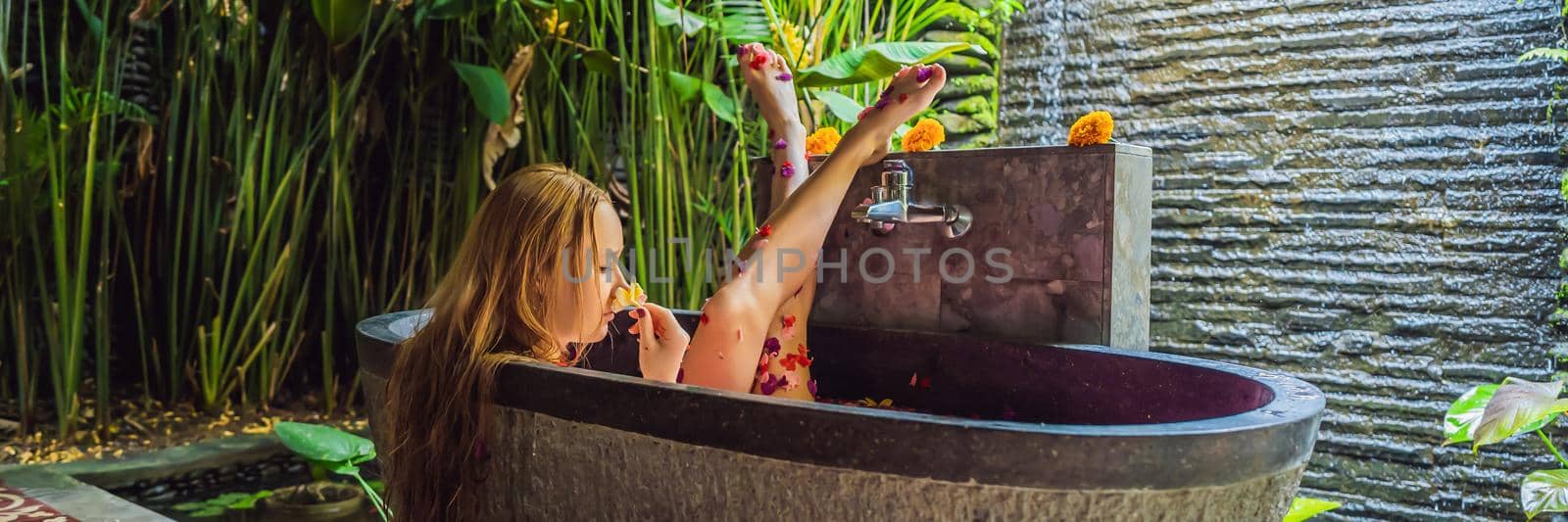 Attractive Young woman in bath with petals of tropical flowers and aroma oils. Spa treatments for skin rejuvenation. Alluring woman in Spa salon. Girl relaxing in bathtub with flower petals. Luxury BANNER, LONG FORMAT by galitskaya