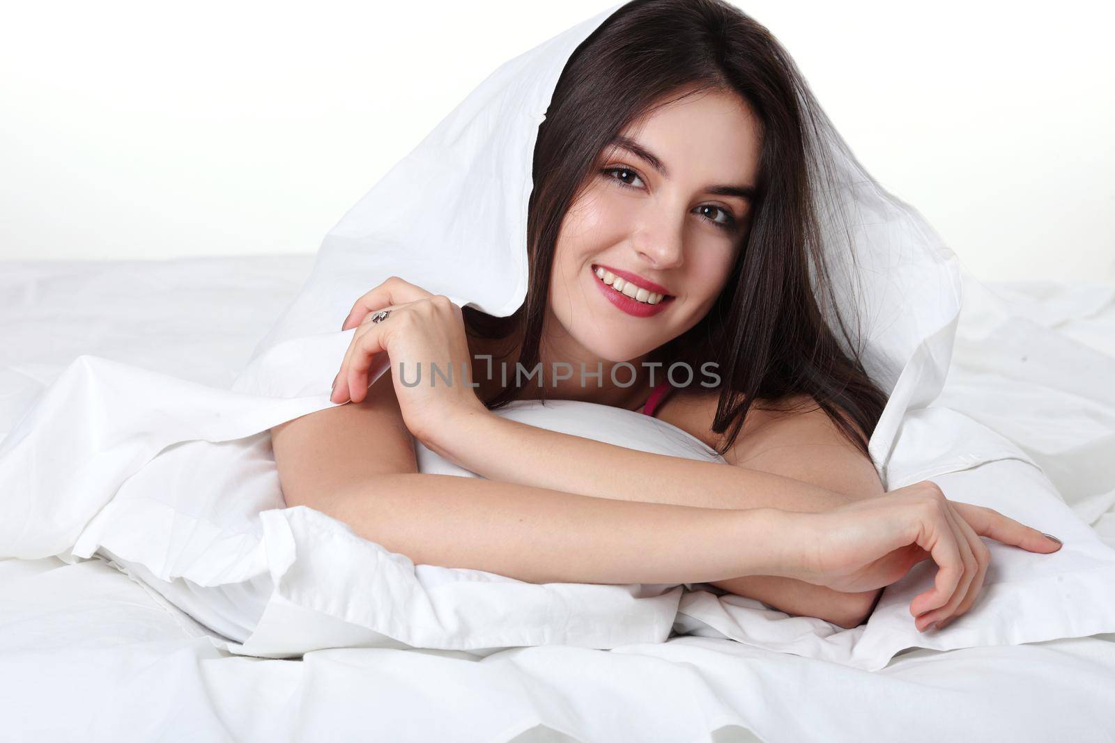 Portrait of a peaceful beautiful woman in bed resting and happy. isolated on white background