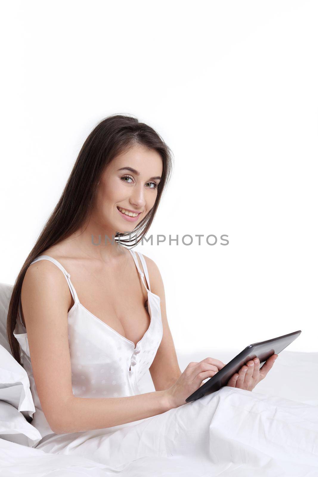Smiling woman catching up on her social media as she relaxes in bed with a laptop computer