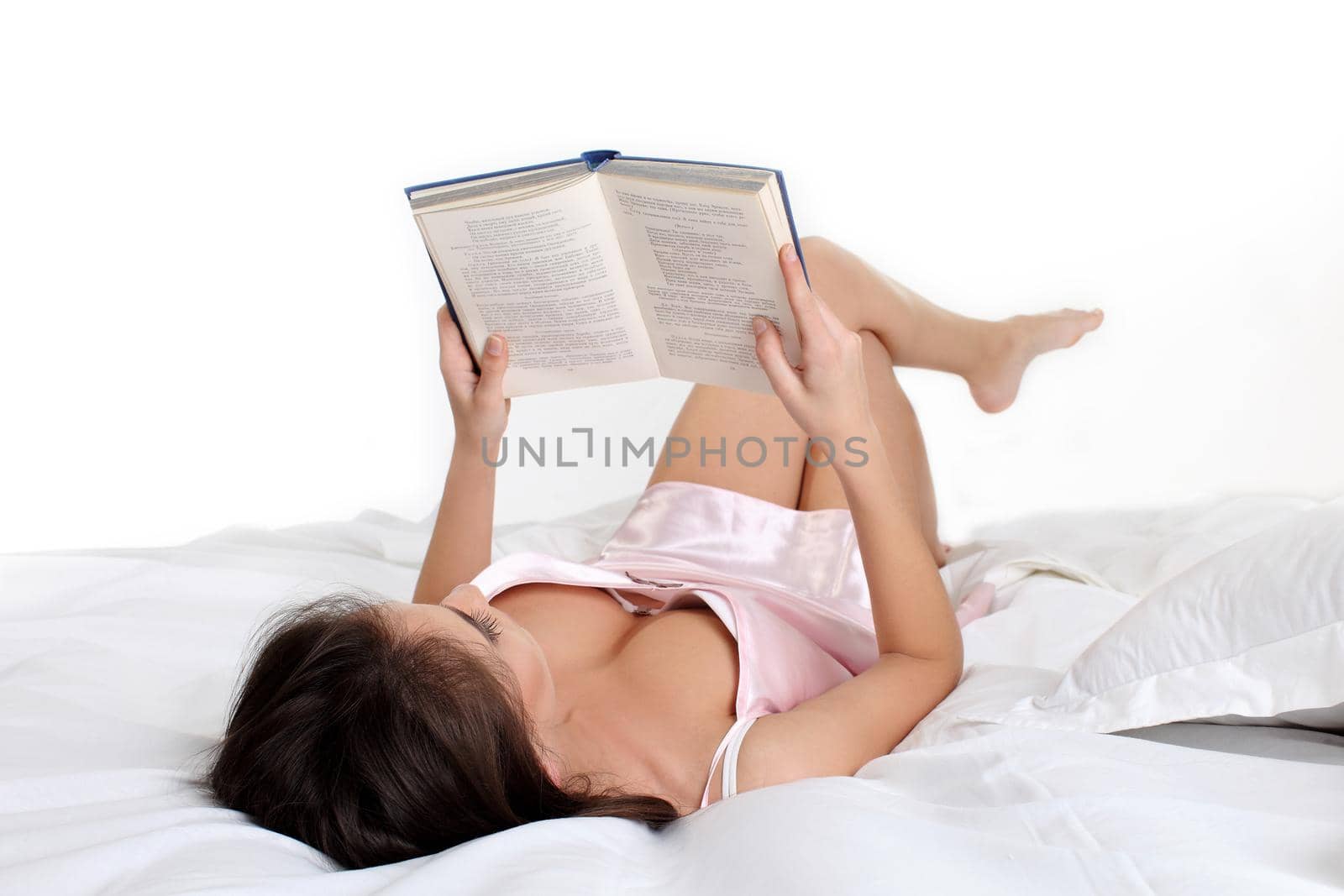 Brunette woman lying in bed reading a book