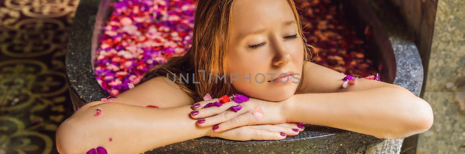 Attractive Young woman in bath with petals of tropical flowers and aroma oils. Spa treatments for skin rejuvenation. Alluring woman in Spa salon. Girl relaxing in bathtub with flower petals. Luxury BANNER, LONG FORMAT by galitskaya