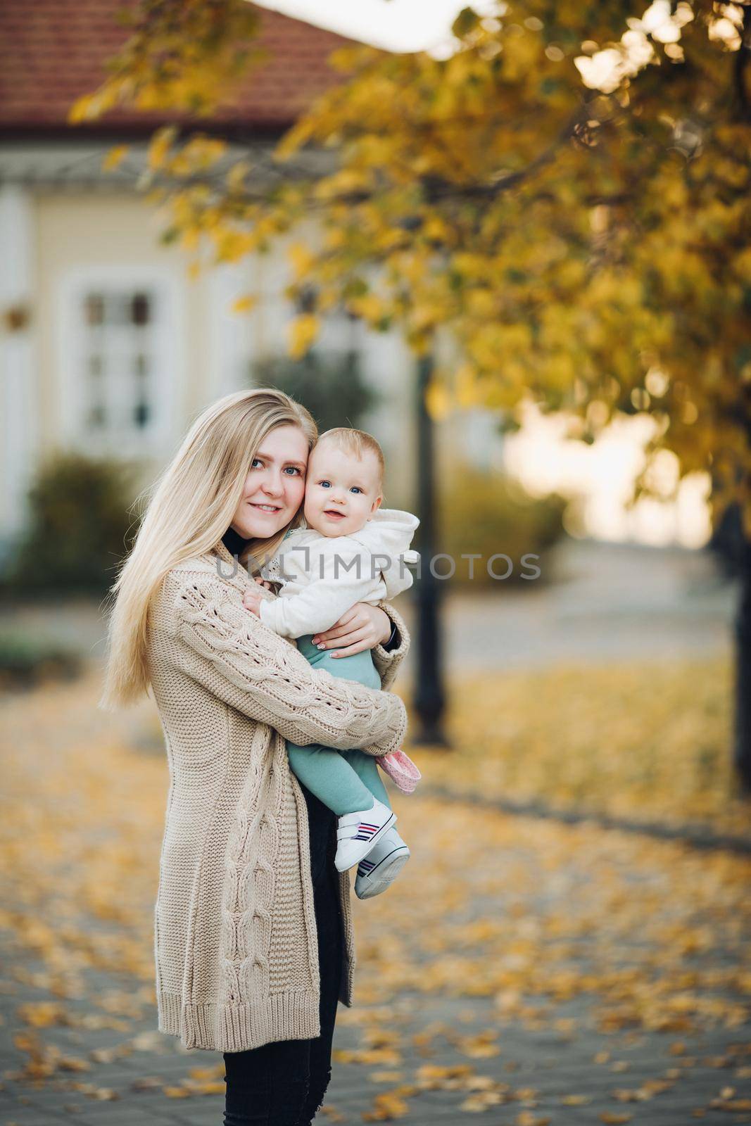 Beautiful mother and daughter walking in the park in autumn, portrait. Mom and daughter, family concept. A little girl in her mother's arms by StudioLucky