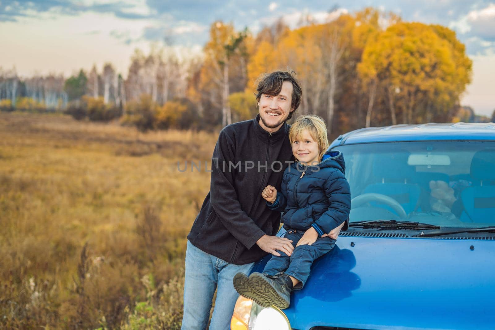 Dad and son are resting on the side of the road on a road trip. Road trip with children concept.