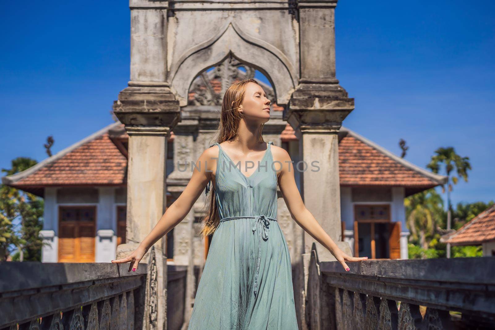 Young woman in dress in Water Palace Soekasada Taman Ujung Ruins on Bali Island in Indonesia. Amazing old architecture. Travel and holidays background.