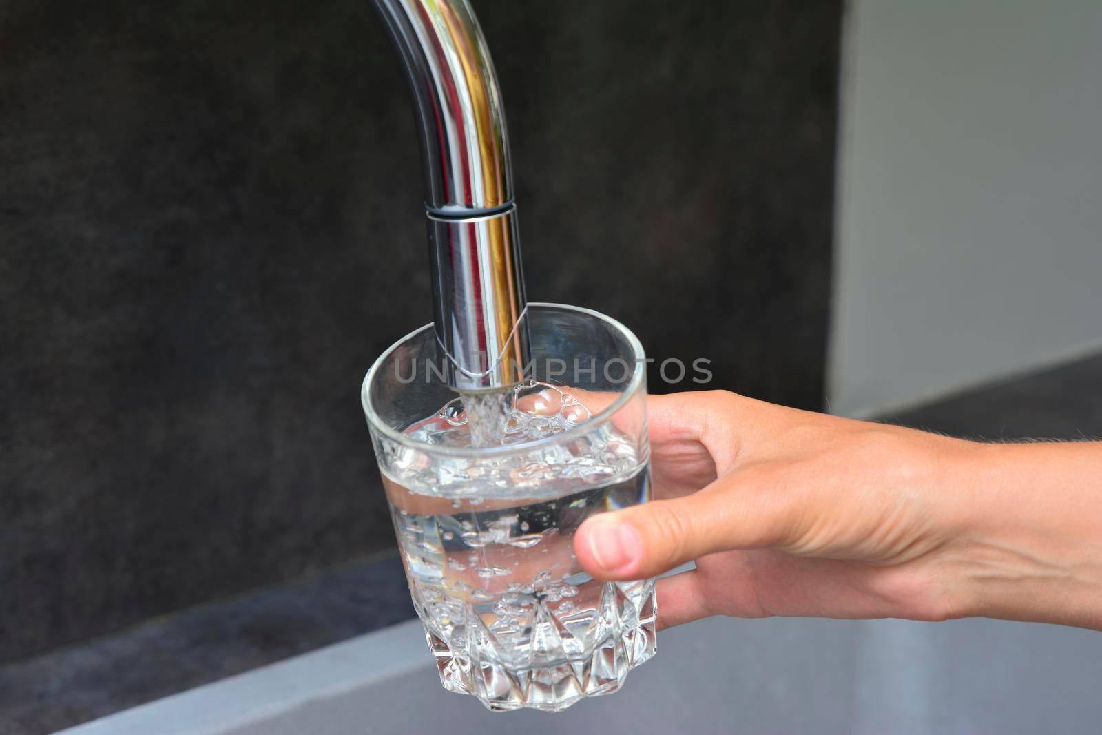 Female hands pouring water in glass on the kitchen