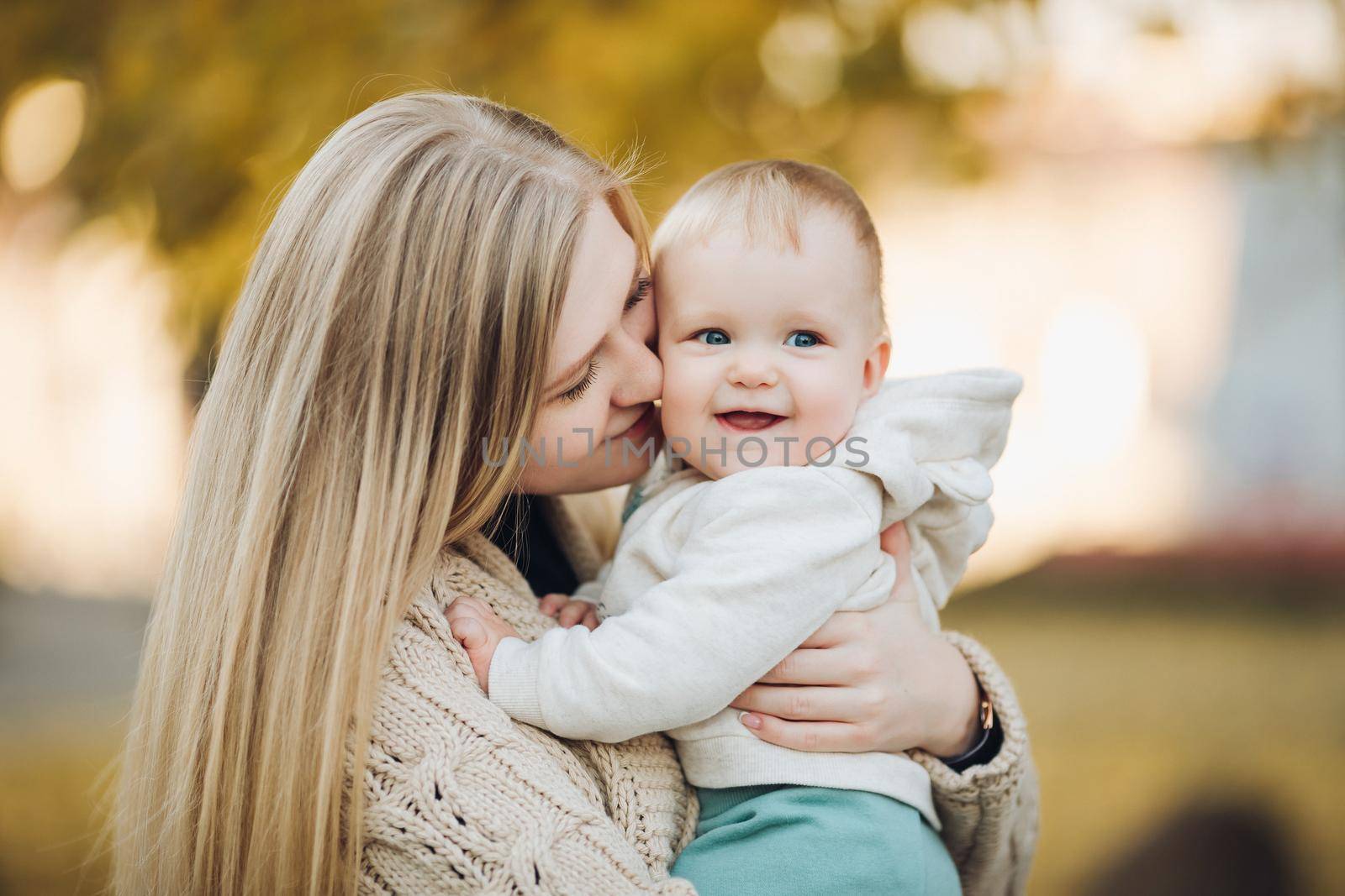 Beautiful mother and daughter walking in the park in autumn, portrait. Mom and daughter, family concept. A little girl in her mother's arms by StudioLucky