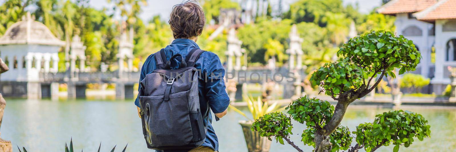 Young man in Water Palace Soekasada Taman Ujung Ruins on Bali Island in Indonesia. Amazing old architecture. Travel and holidays background. BANNER, LONG FORMAT