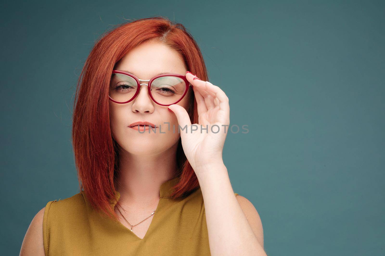 Fashion studio portrait of pretty young hipster red hair woman with bright sexy make up and glasses , wearing stylish urban t shirt, Blue wall background.