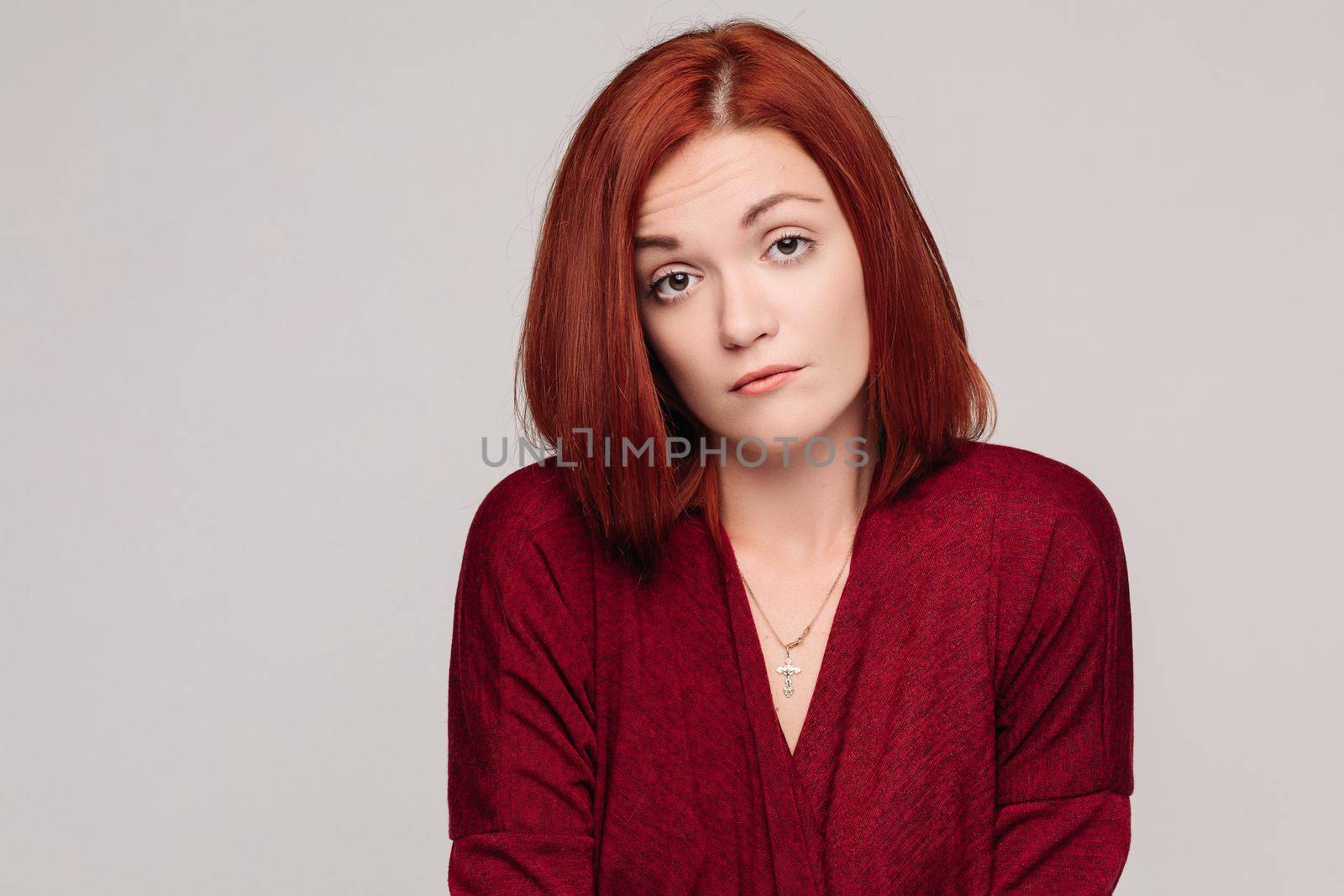 Front view of beautiful business woman wearing in red with short haircut having disregard and passive emotion, looking at camera. Girl do not understanding why and looking frustrated.