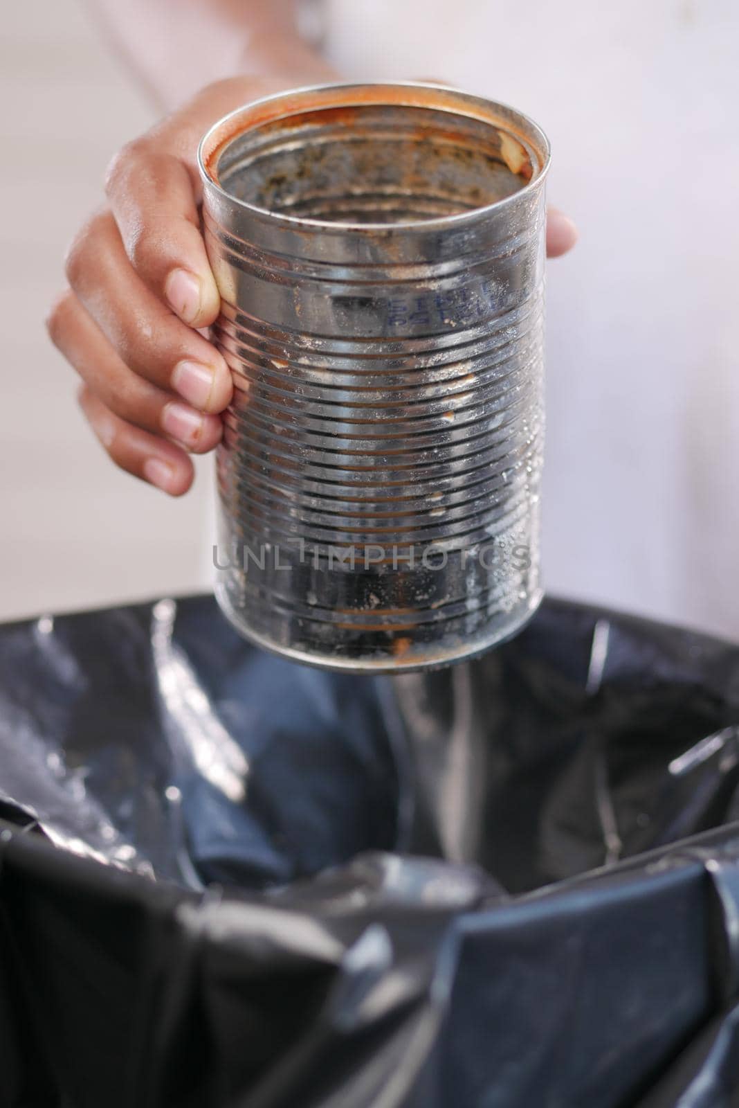 throwing tin container in a garbage bin .