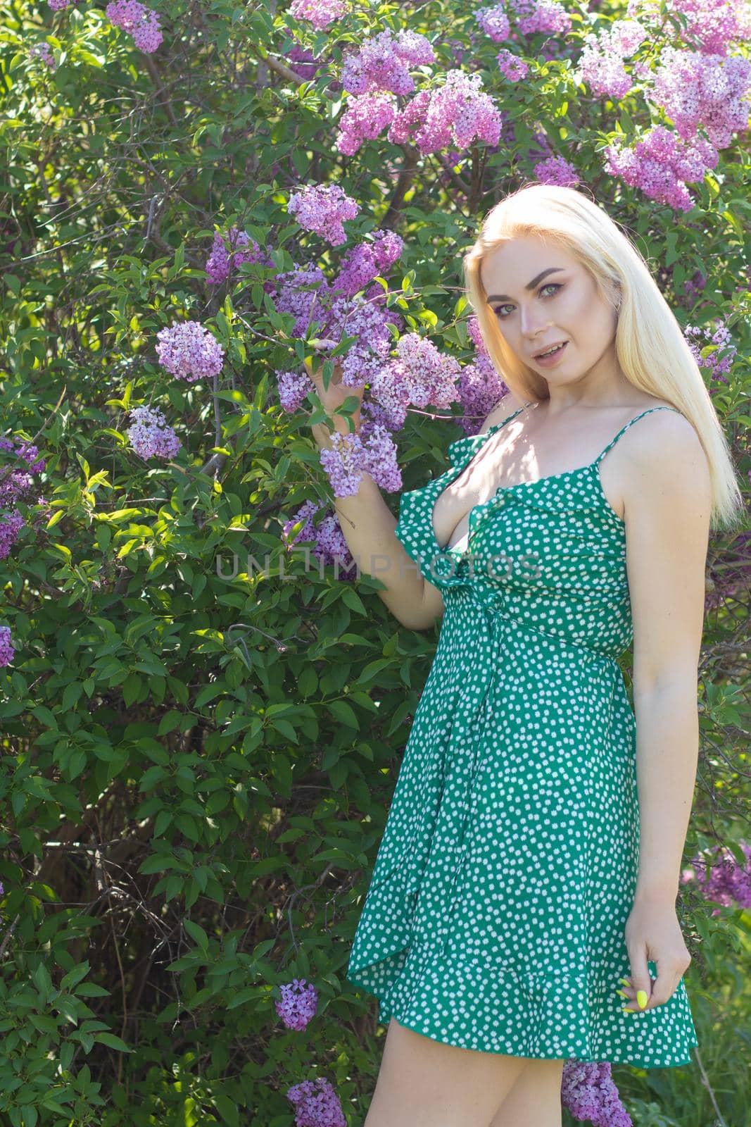 Fashionable girl model near a lilac bush. Spring flowers and beautiful blonde woman. Model appearance. Soft focus