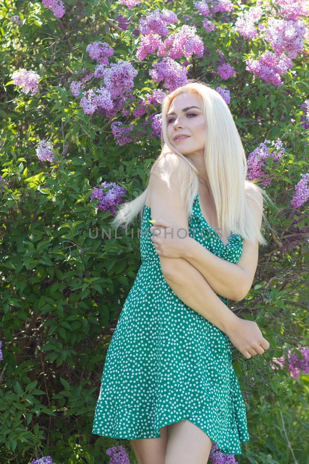 Fashionable girl model near a lilac bush. Spring flowers and beautiful blonde woman. Model appearance. Soft focus