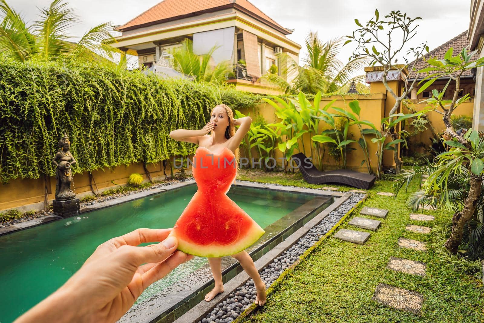 Young woman in a watermelon dress on a pool background. The concept of summer, diet and healthy eating.