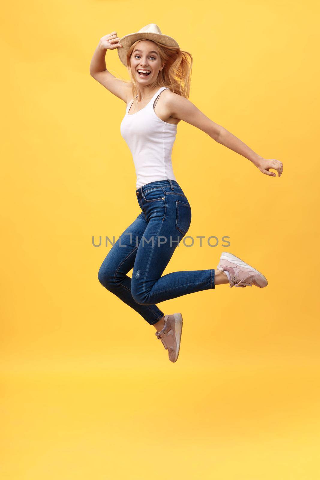 Happiness, dream, fun, joy, summer concept. Very excited happy cute caucasian teen is jumping up, in summer outfit, hat, on bright yellow background.