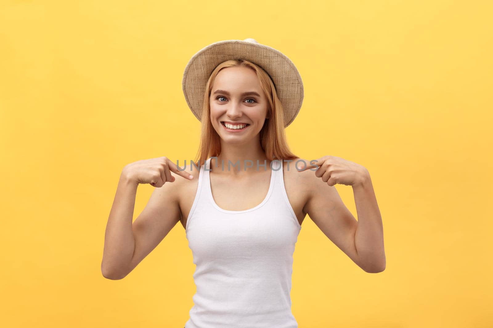 Clothing, design and advertising concept. Indoor shot of positive friendly young female pointing at copy space on her blank white t-shirt for your text or promotional content by Benzoix