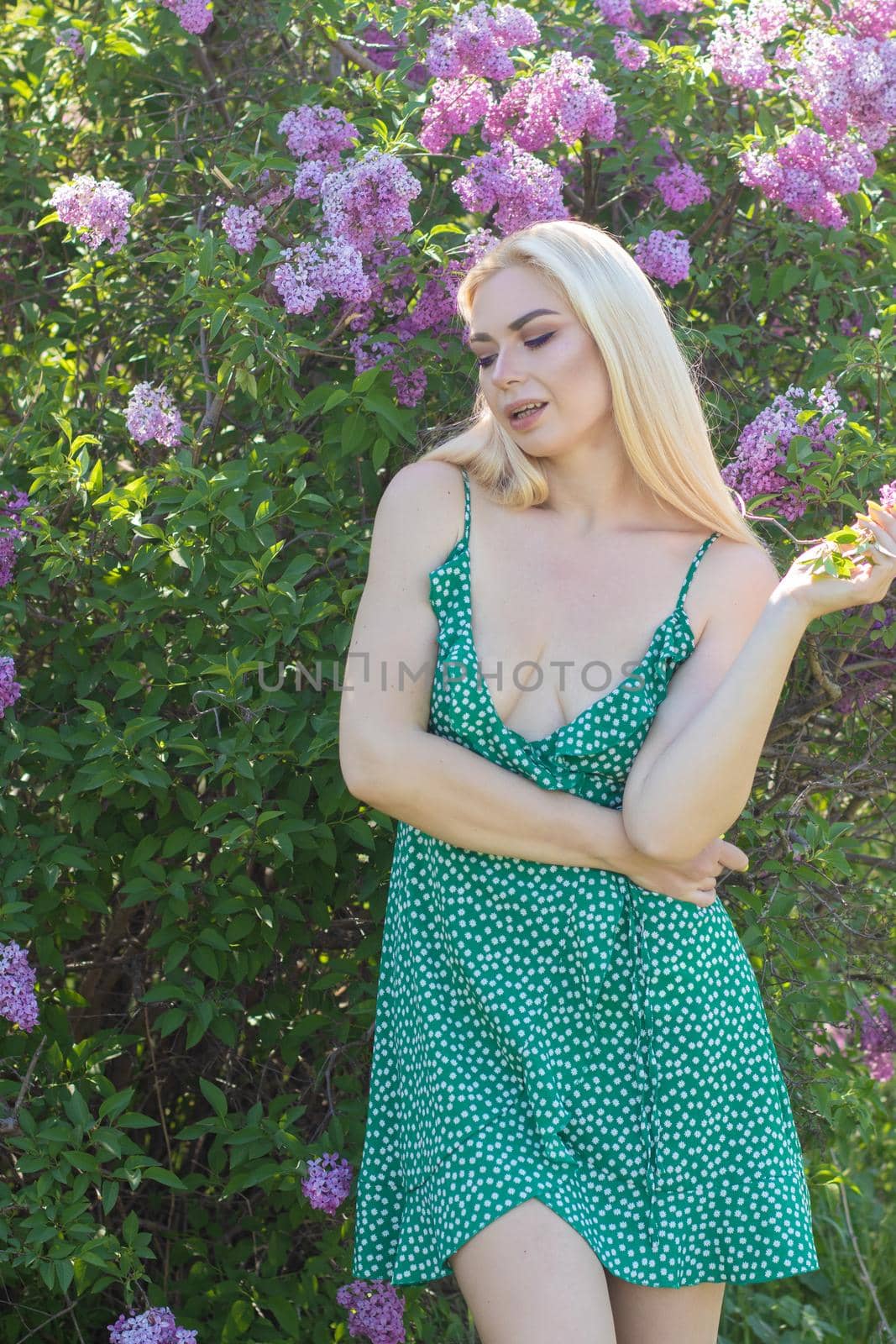 Fashionable girl model near a lilac bush. Spring flowers and beautiful blonde woman. Model appearance. Soft focus