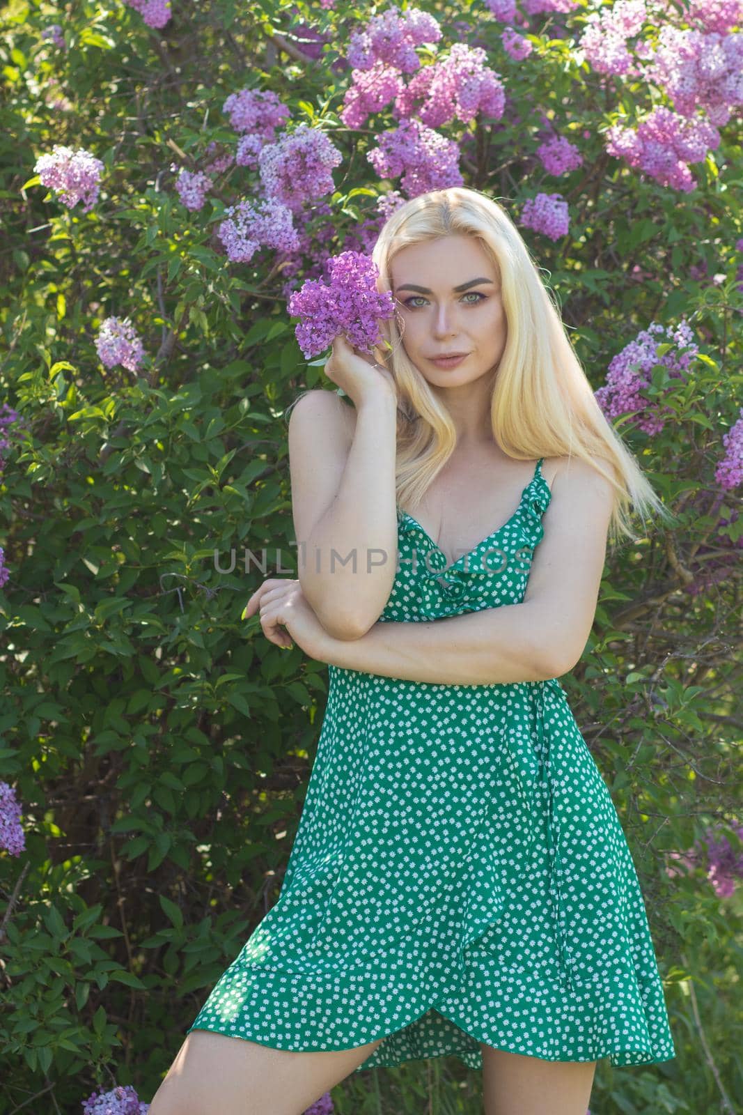 Fashionable girl model near a lilac bush. Spring flowers and beautiful blonde woman. Model appearance. Soft focus