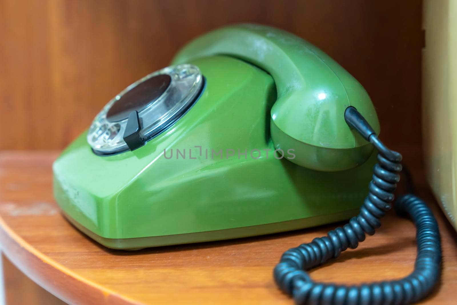 green vintage phone with a rotating dial dial. the phone with the receiver on the shelf