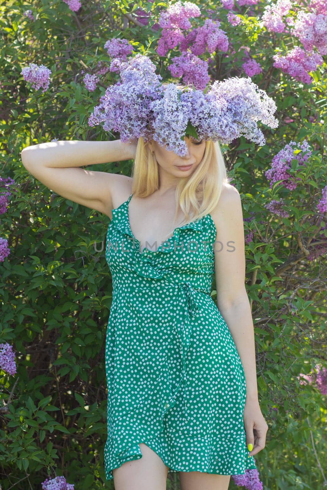 Beautiful woman in lilac Garden. Girl with lilac wreath in springtime. Gardening. Soft focus